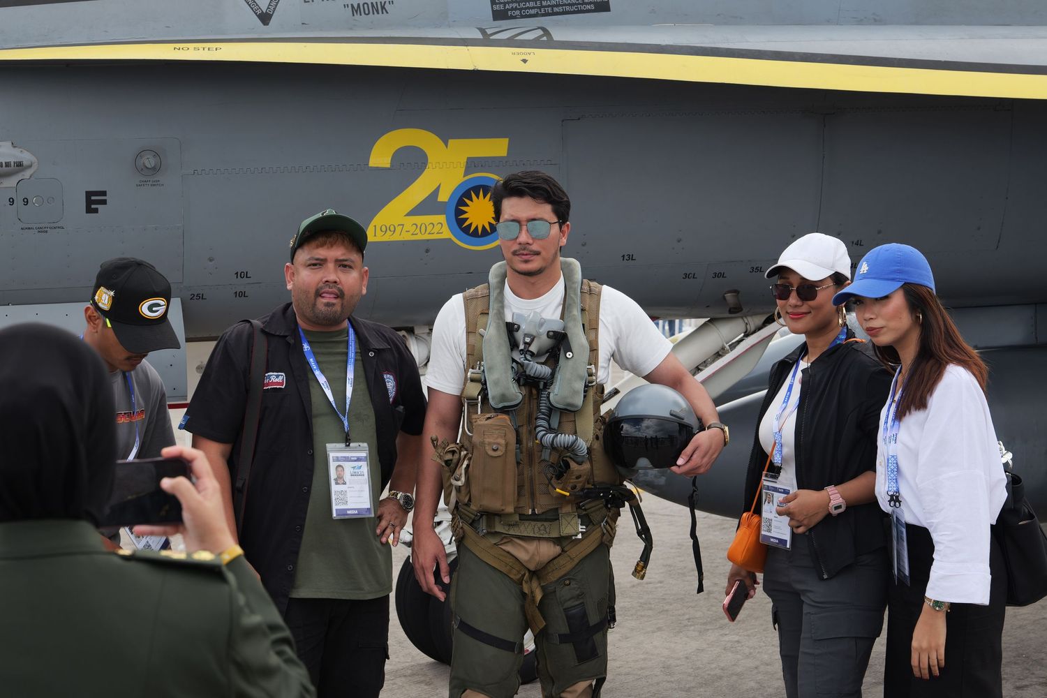 Military personnel and aviation enthusiasts gather around an aircraft marked with number 25 at an airshow event.