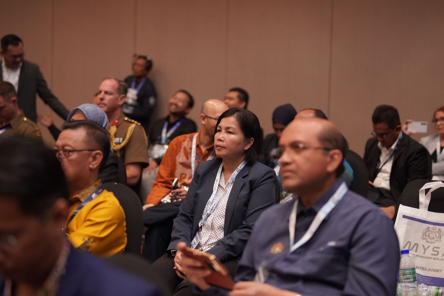 Engaged audience members watch presentation during professional conference session.