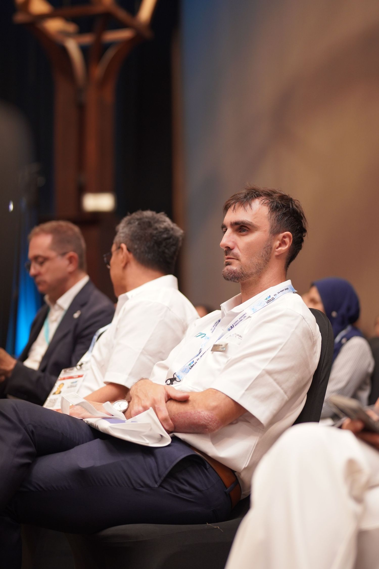 Attentive conference attendees in business attire sit and listen during a professional event in an elegant venue.