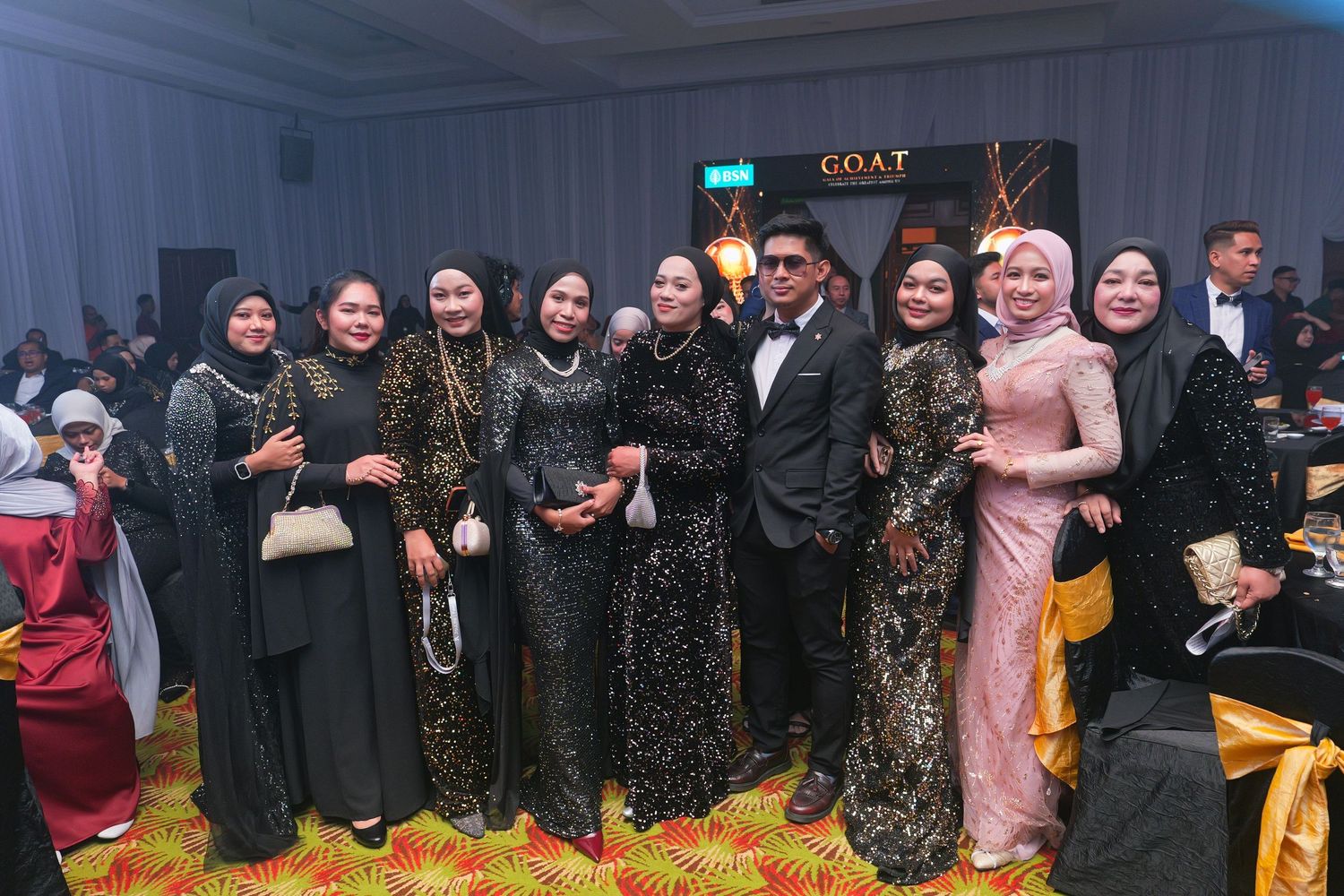 Group of elegantly dressed attendees posing together at BSN G.O.A.T Gala Dinner.