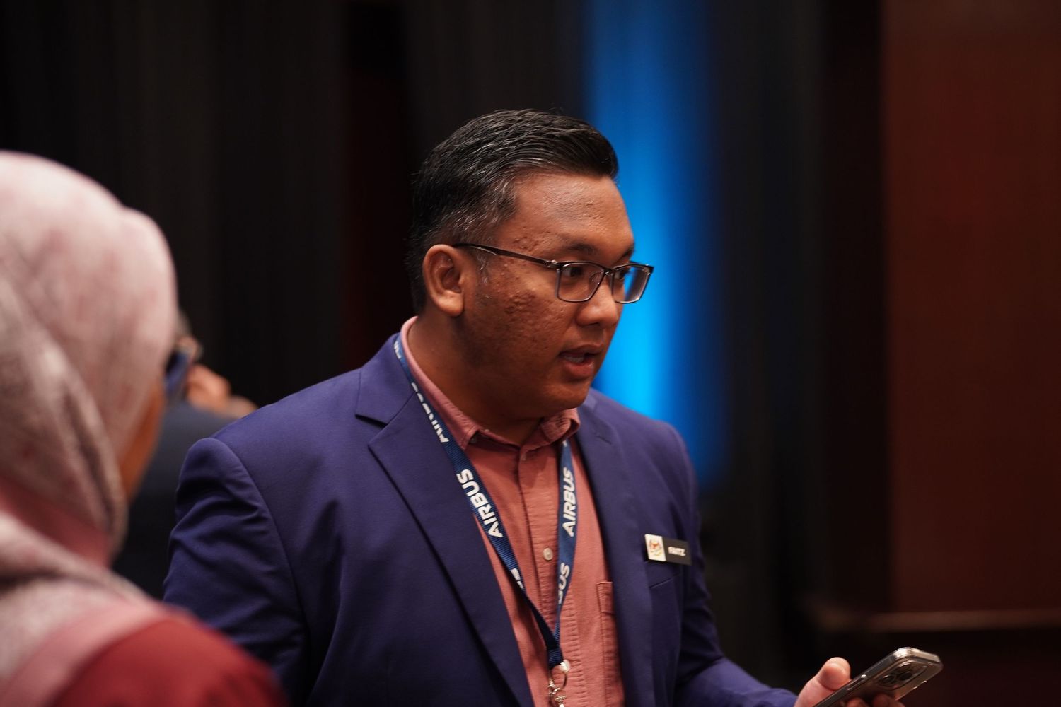 Speaker at professional conference gestures while delivering presentation from podium.