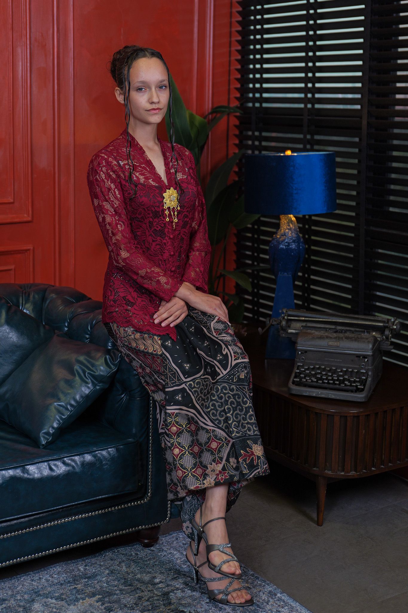 A series of four similar photos showing someone seated on a dark leather couch wearing a burgundy top and patterned skirt.