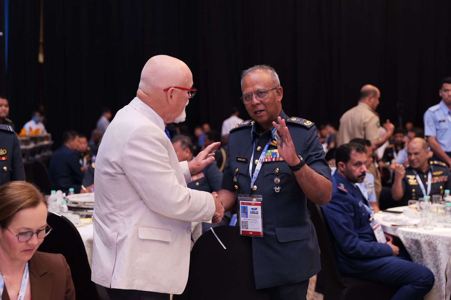 Conference attendees in military and civilian attire socialize during a formal event.