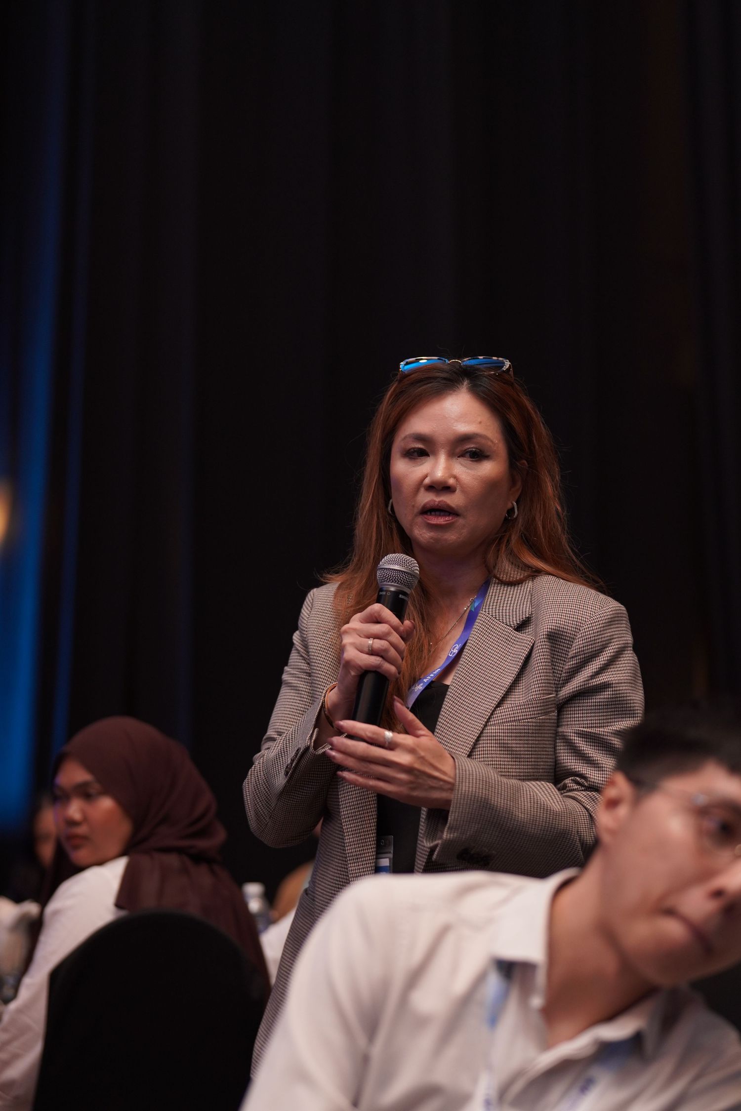 Attendee asking question during conference Q&A session in auditorium.