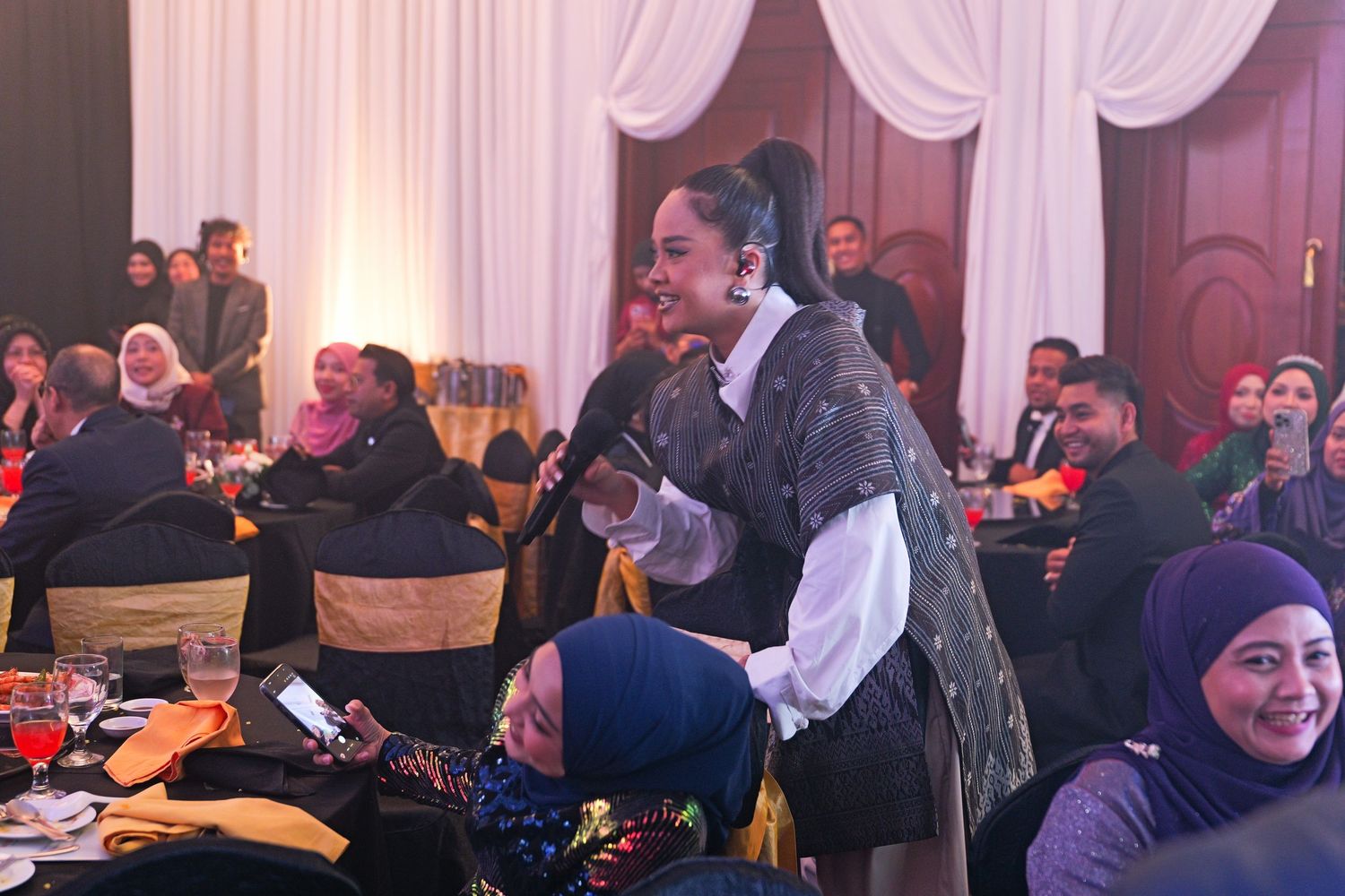 Woman stands to speak during an elegant corporate awards dinner banquet event.