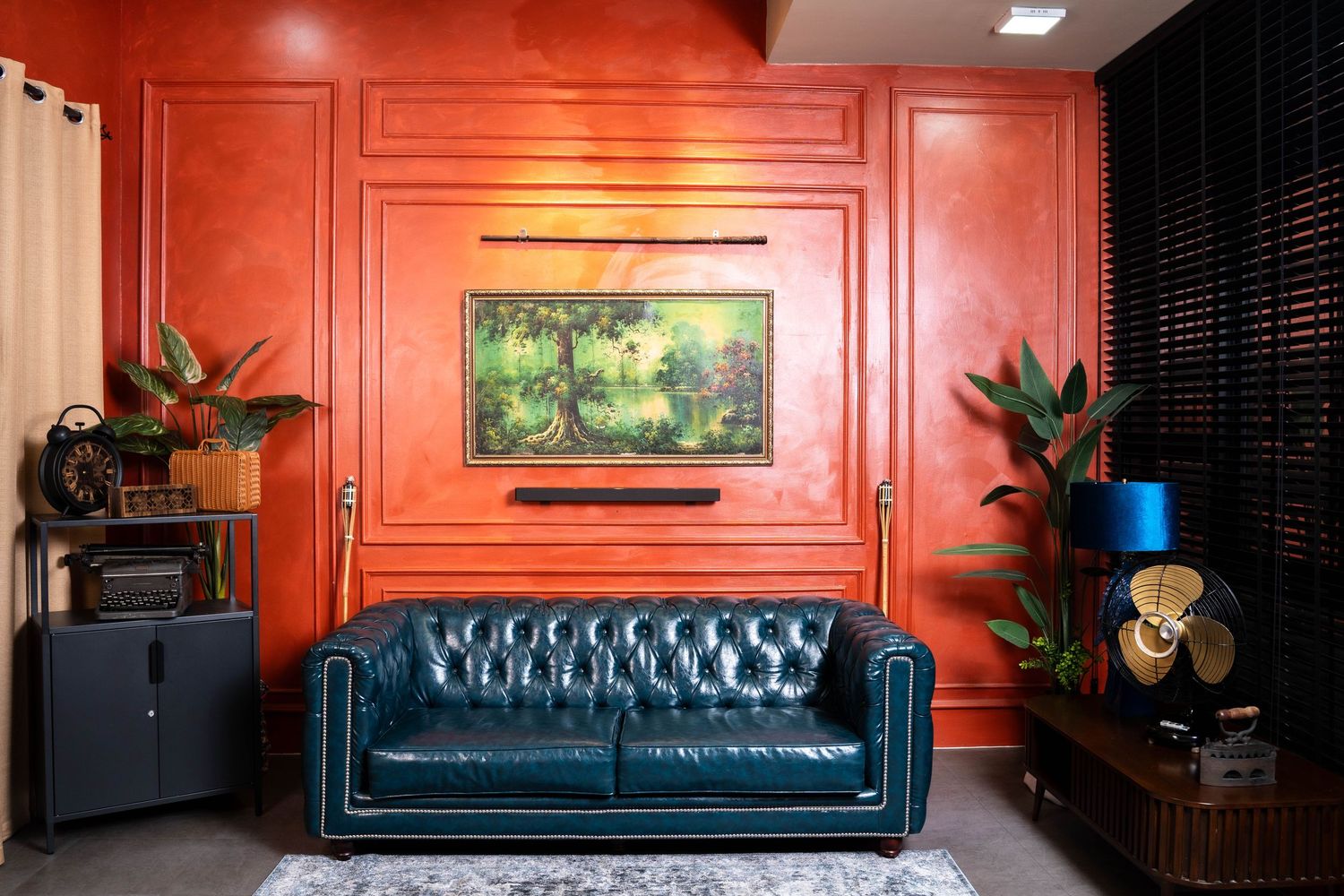 Modern living room interior with red walls, teal velvet sofa, and contemporary decor in moody lighting.