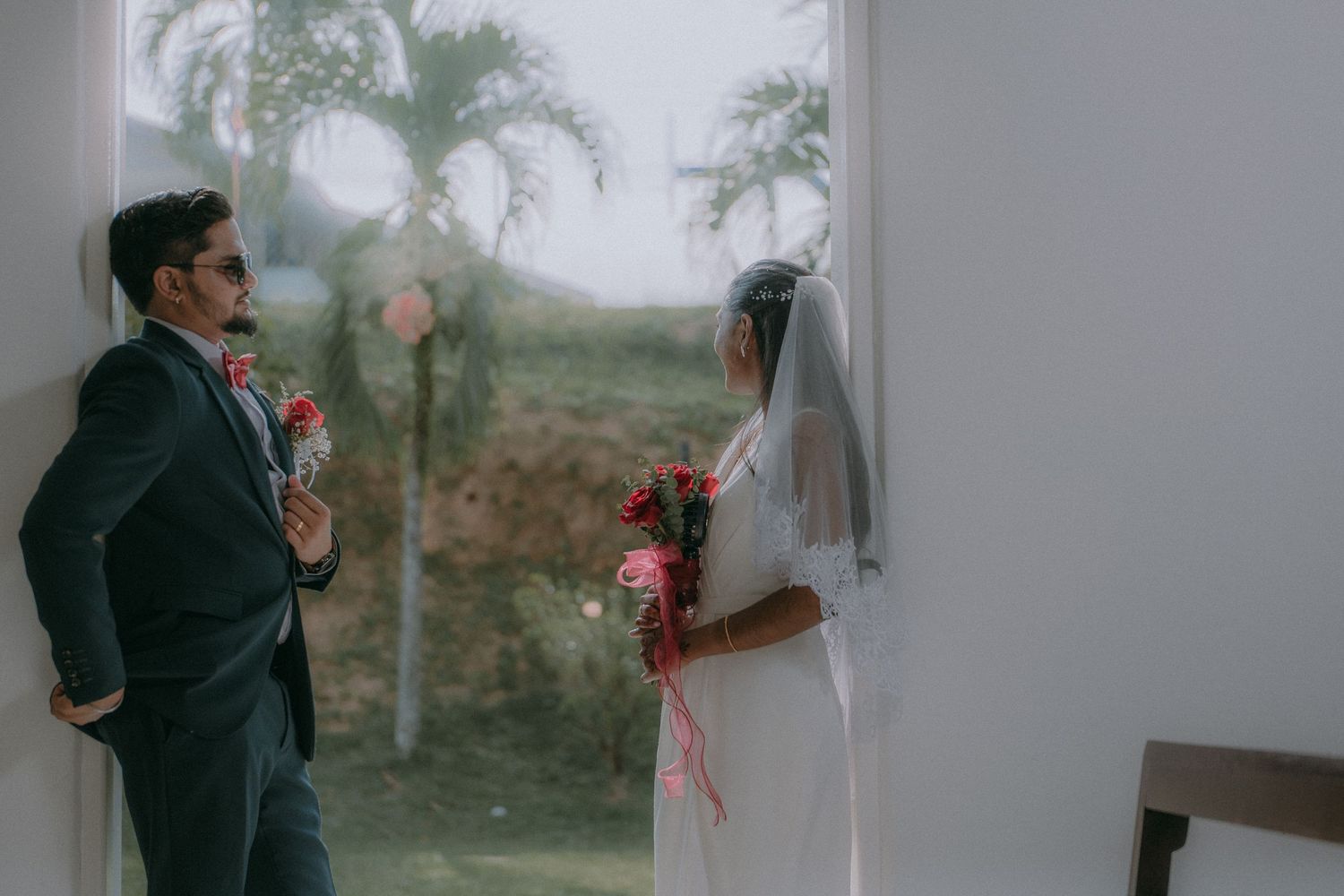 A couple in wedding attire shares a romantic moment against a misty outdoor backdrop.