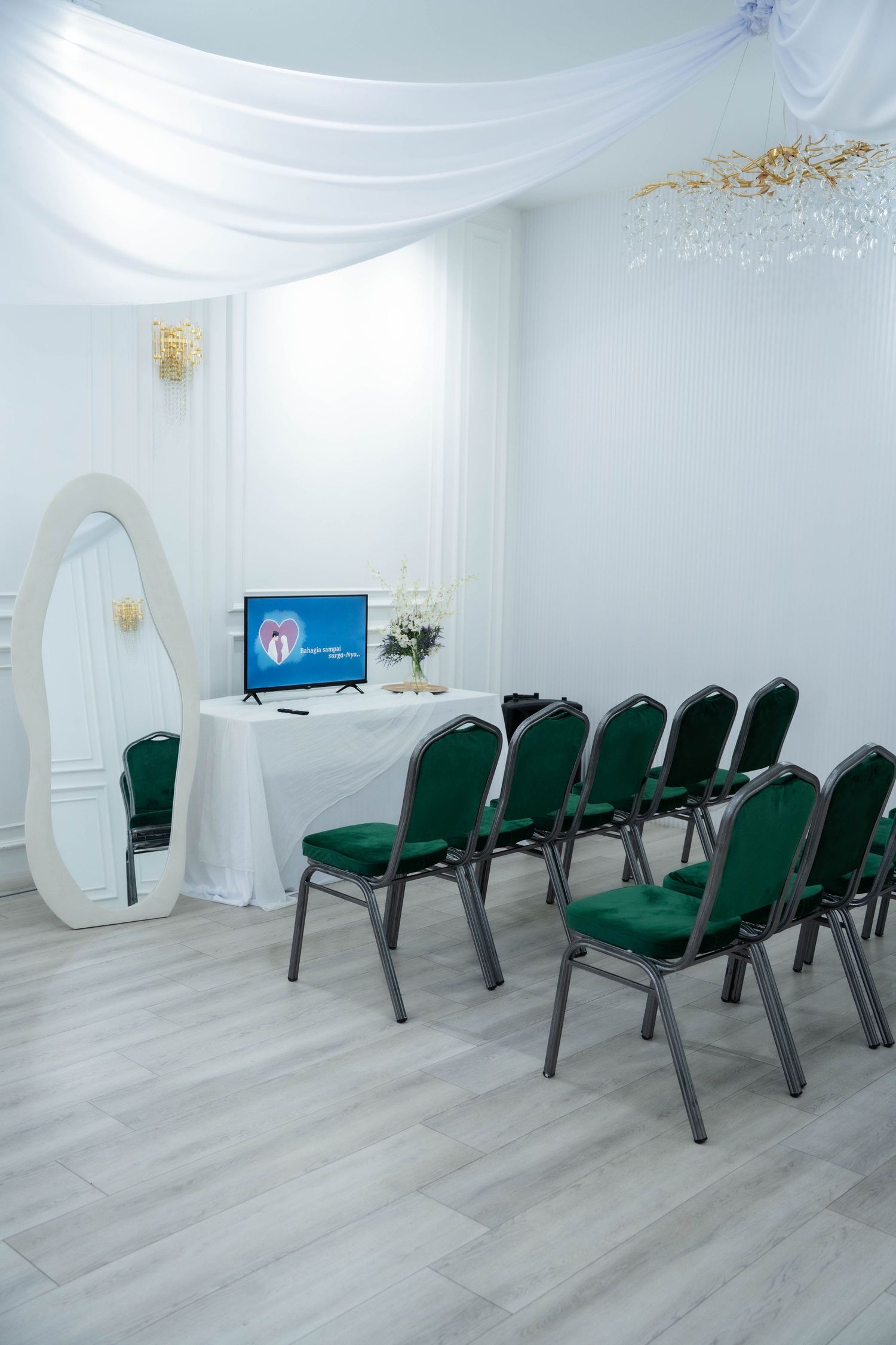 White event space with green chairs arranged in rows and draped fabric ceiling creates an elegant meeting setup.