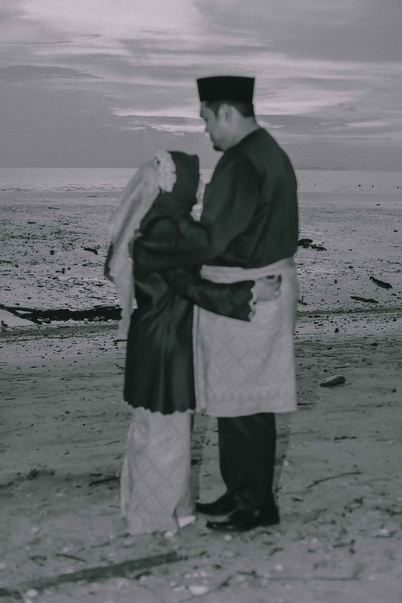 Black and white vintage photo of two people walking along a beach shoreline.