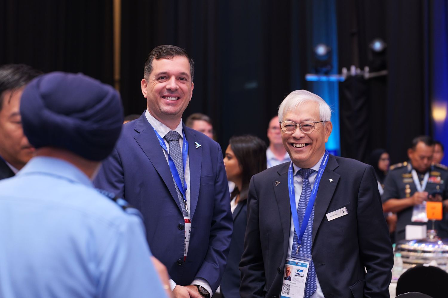 Military and business professionals networking at a formal conference event with blue lighting and formal attire.