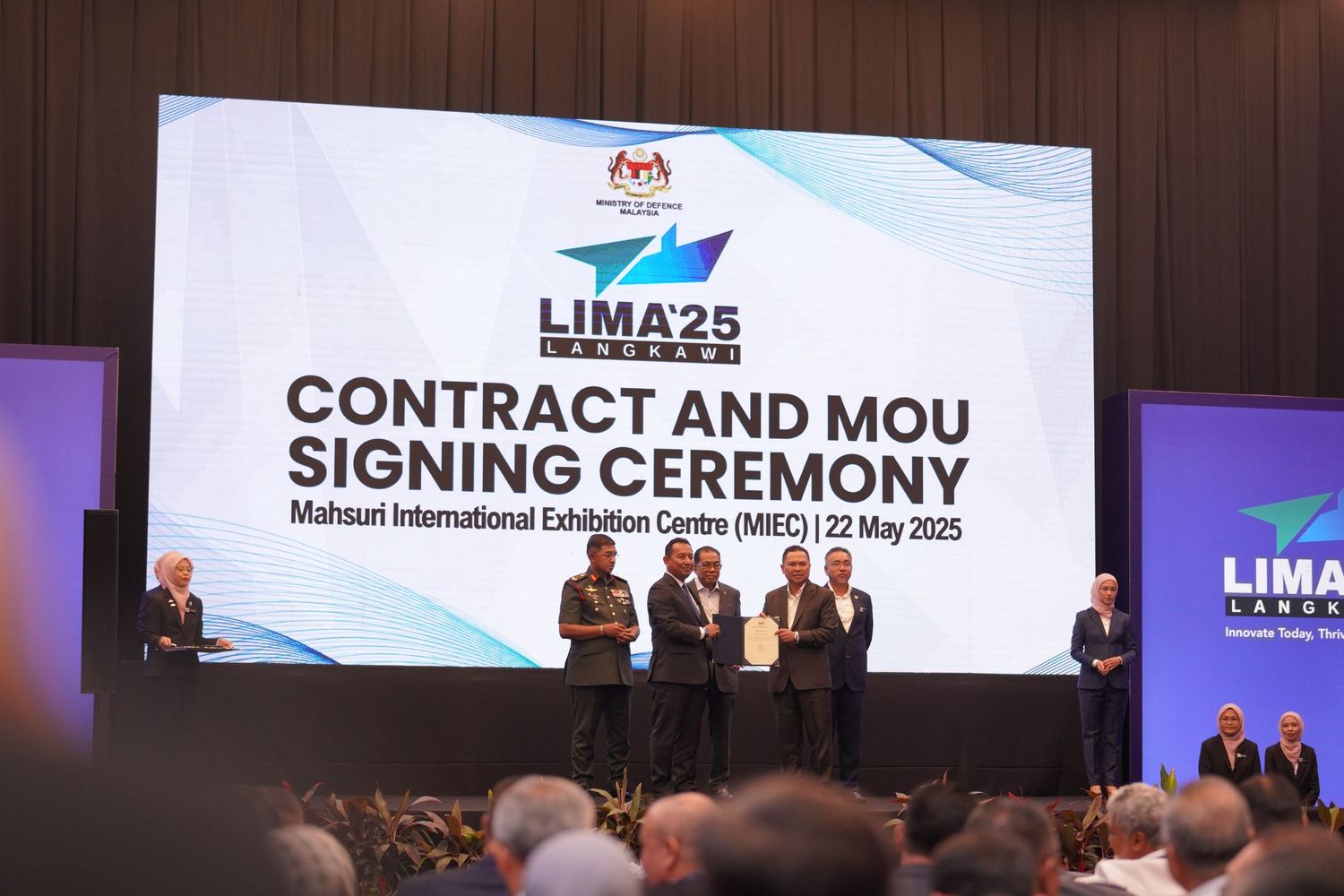 Contract and MOU signing ceremony event at LIMA25 conference with officials standing on stage in front of large screen.
