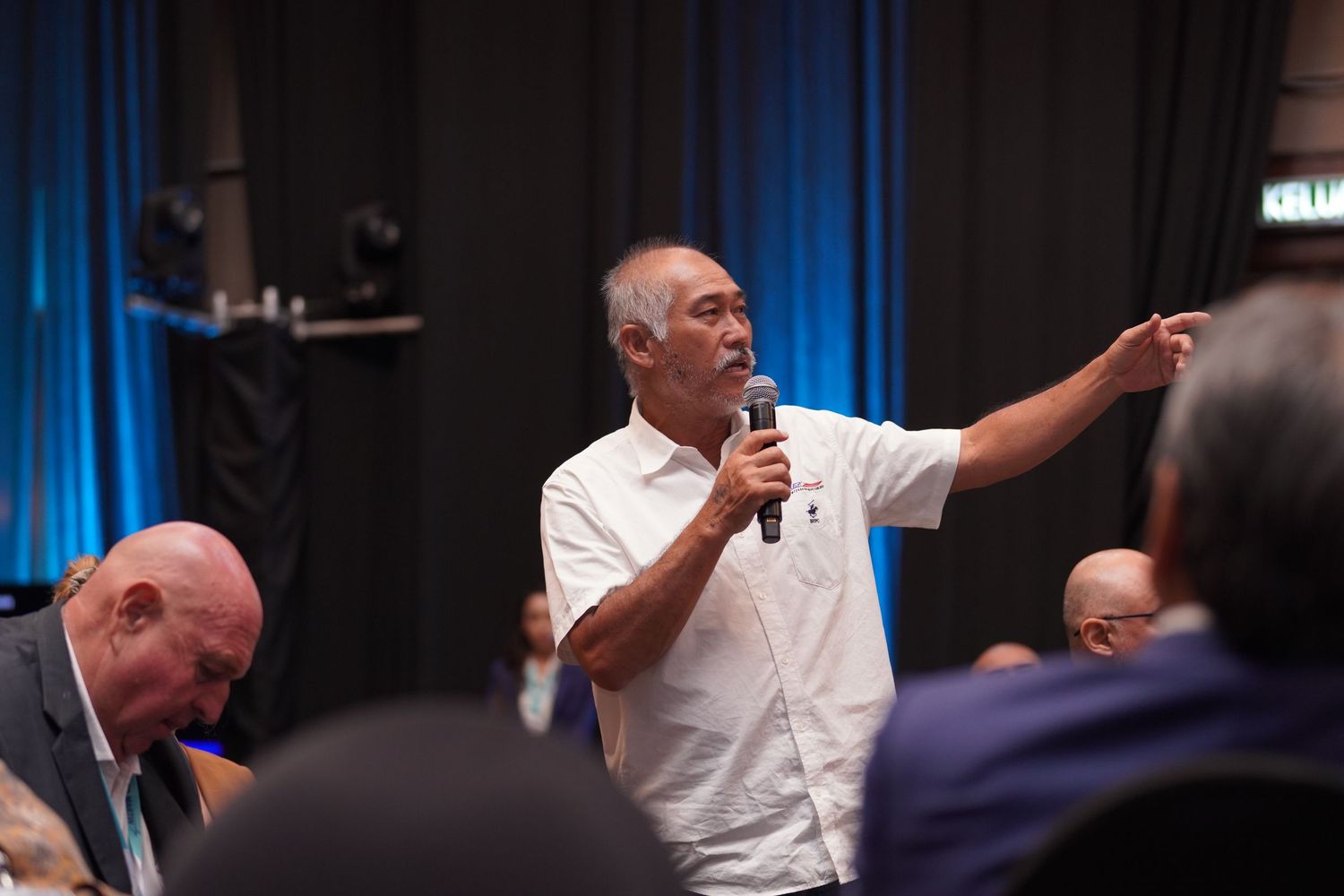 Speaker in white shirt gesturing while presenting at conference session.