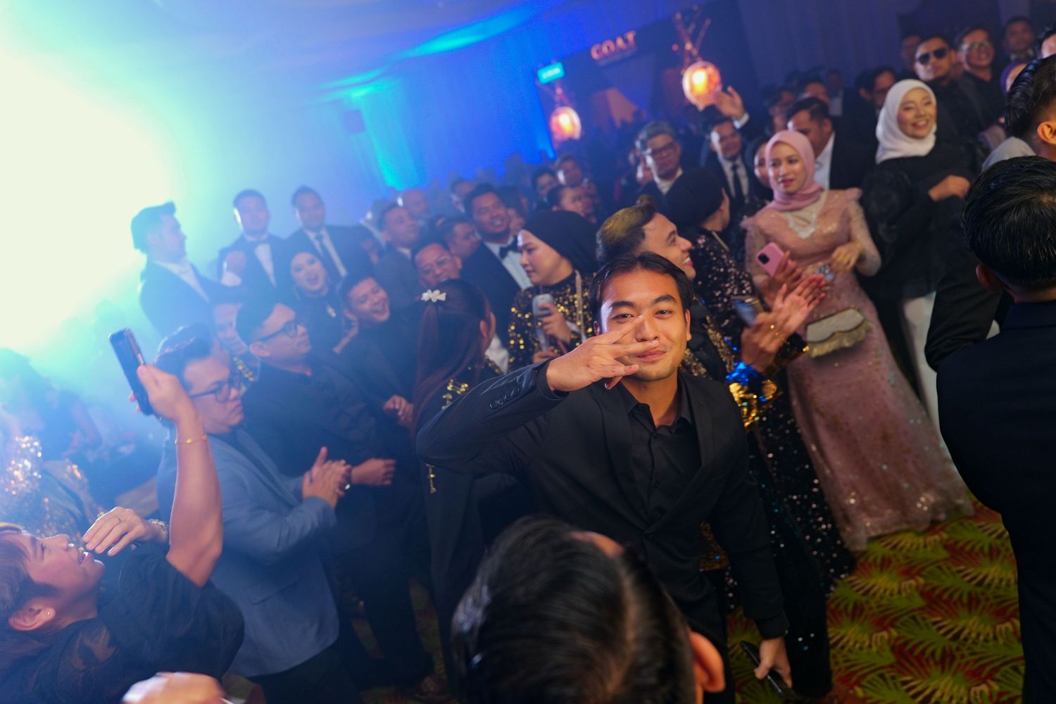Guests dance and celebrate under blue and red lights at a festive evening event.