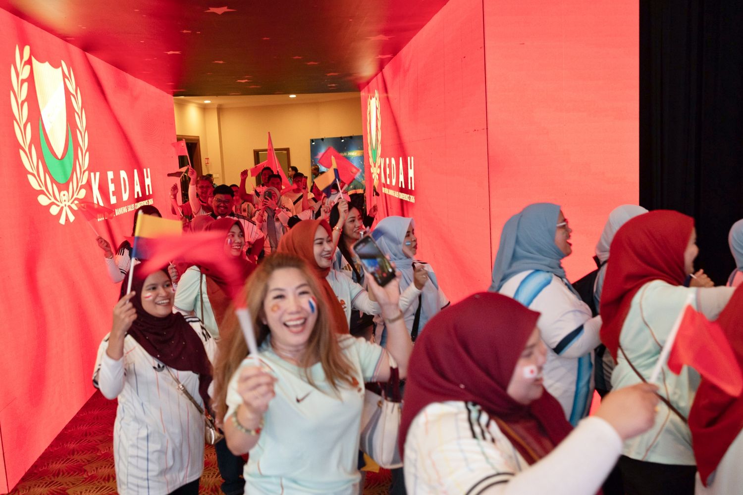 Excited women waving Kedah flags at a vibrant political rally event in Malaysia.