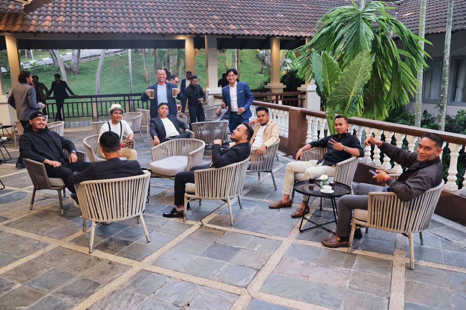 Business professionals gathered on an outdoor terrace having a meeting in a lush garden setting.
