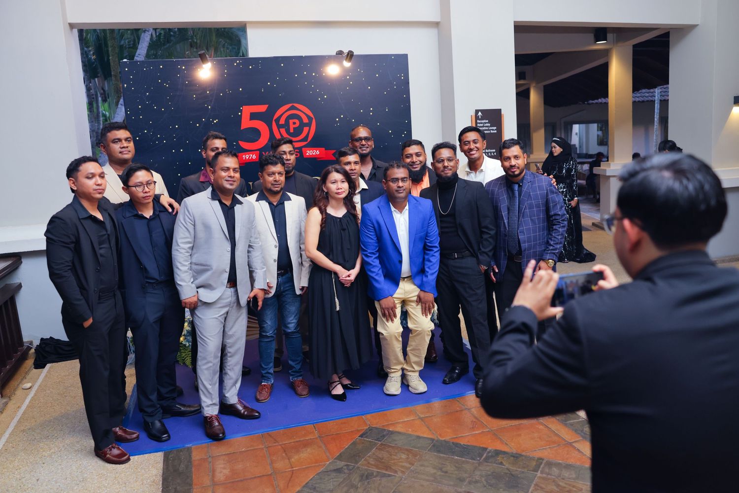 Group of professionals posing for a photo at a 50th anniversary corporate event with a decorative backdrop.