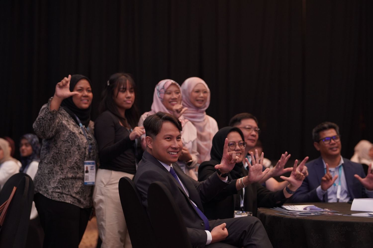 Audience members engaged in conversation during a business conference in dark auditorium setting.