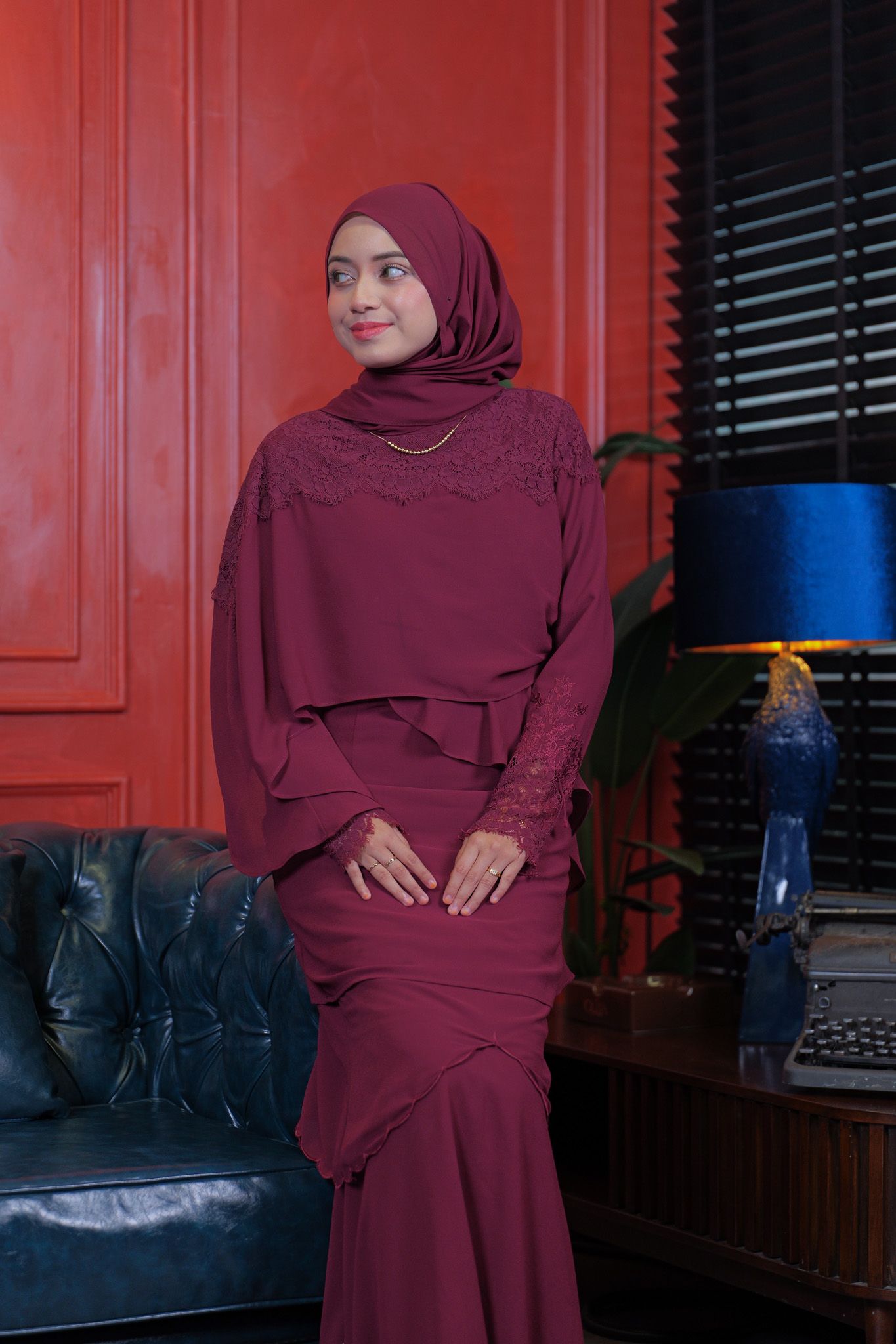 A series of four connected photos showing someone in a burgundy hijab and dress posing against a red wall with dark furniture.