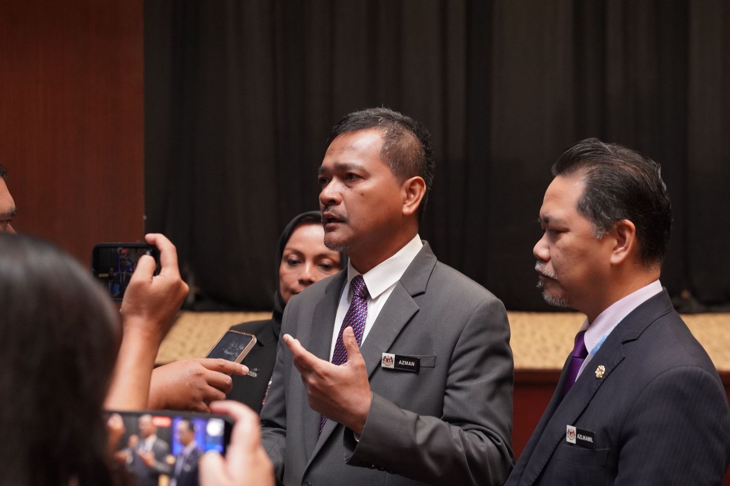 Professional speaker gesturing while giving presentation with colleagues at business conference.
