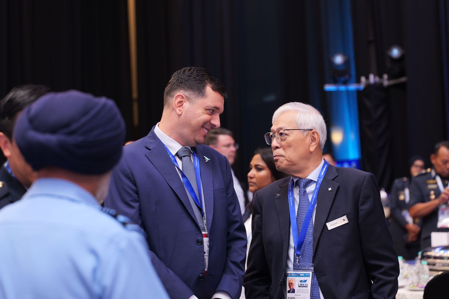 Two attendees having a discussion during a formal conference gathering.