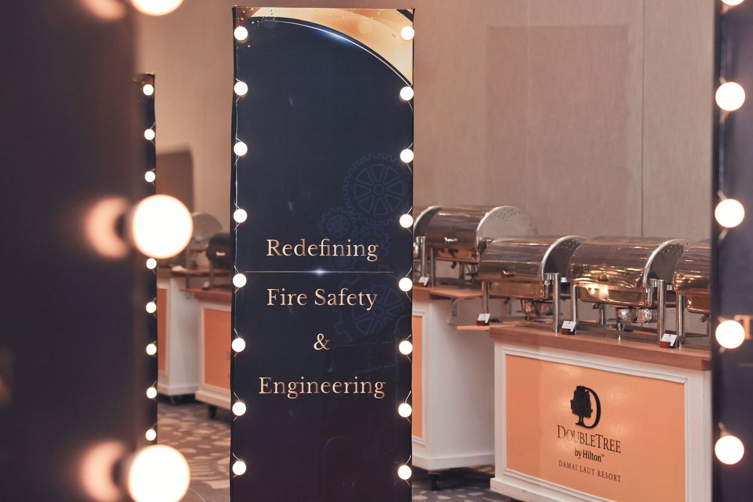 Illuminated vanity mirror display reading Redefining Fire Safety and Engineering at DoubleTree hotel event.