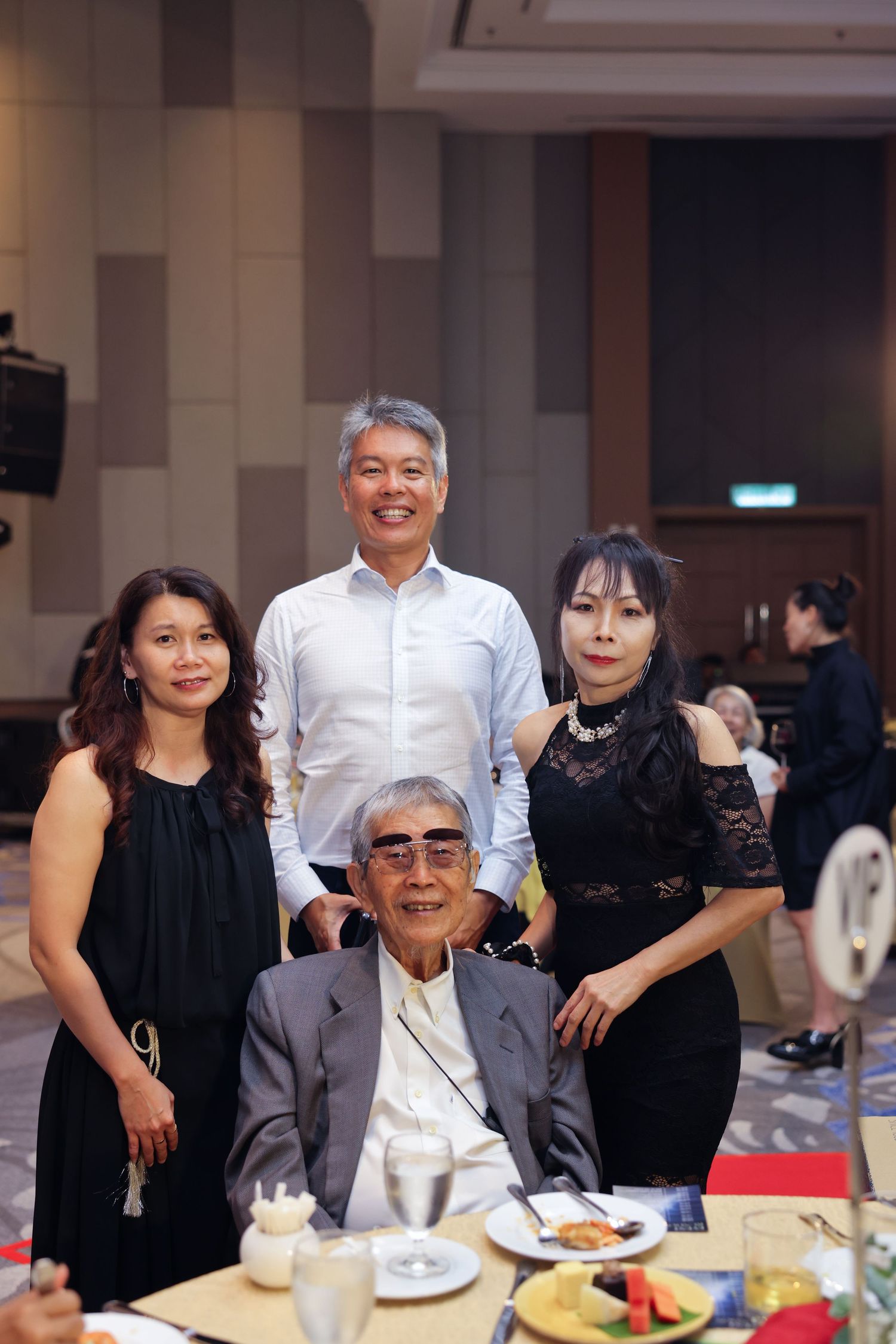 Four Asian family members pose together at a formal banquet dinner event in an elegant ballroom.