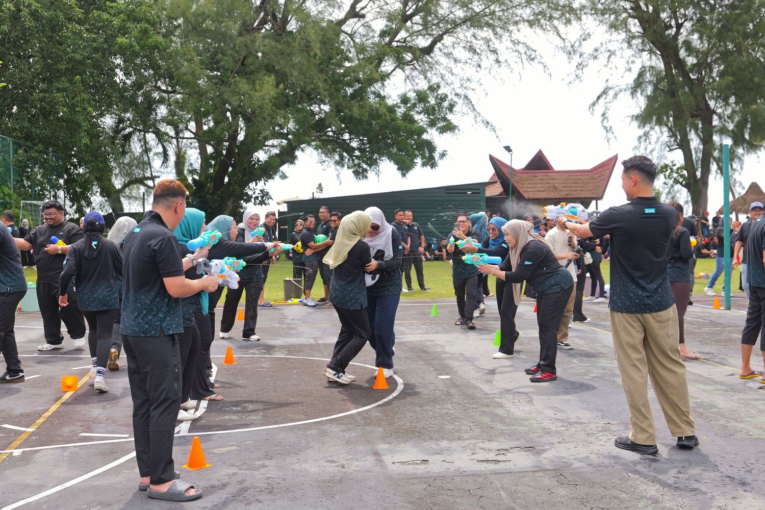 Corporate team building activity with employees playing outdoor balloon game on court.