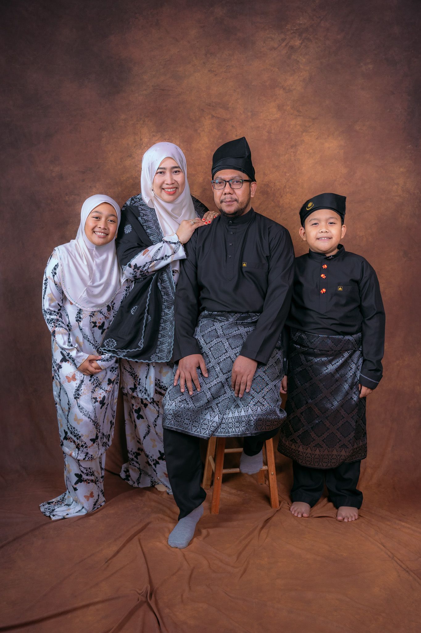 Family portrait series with matching outfits against brown backdrop showing different poses and expressions.