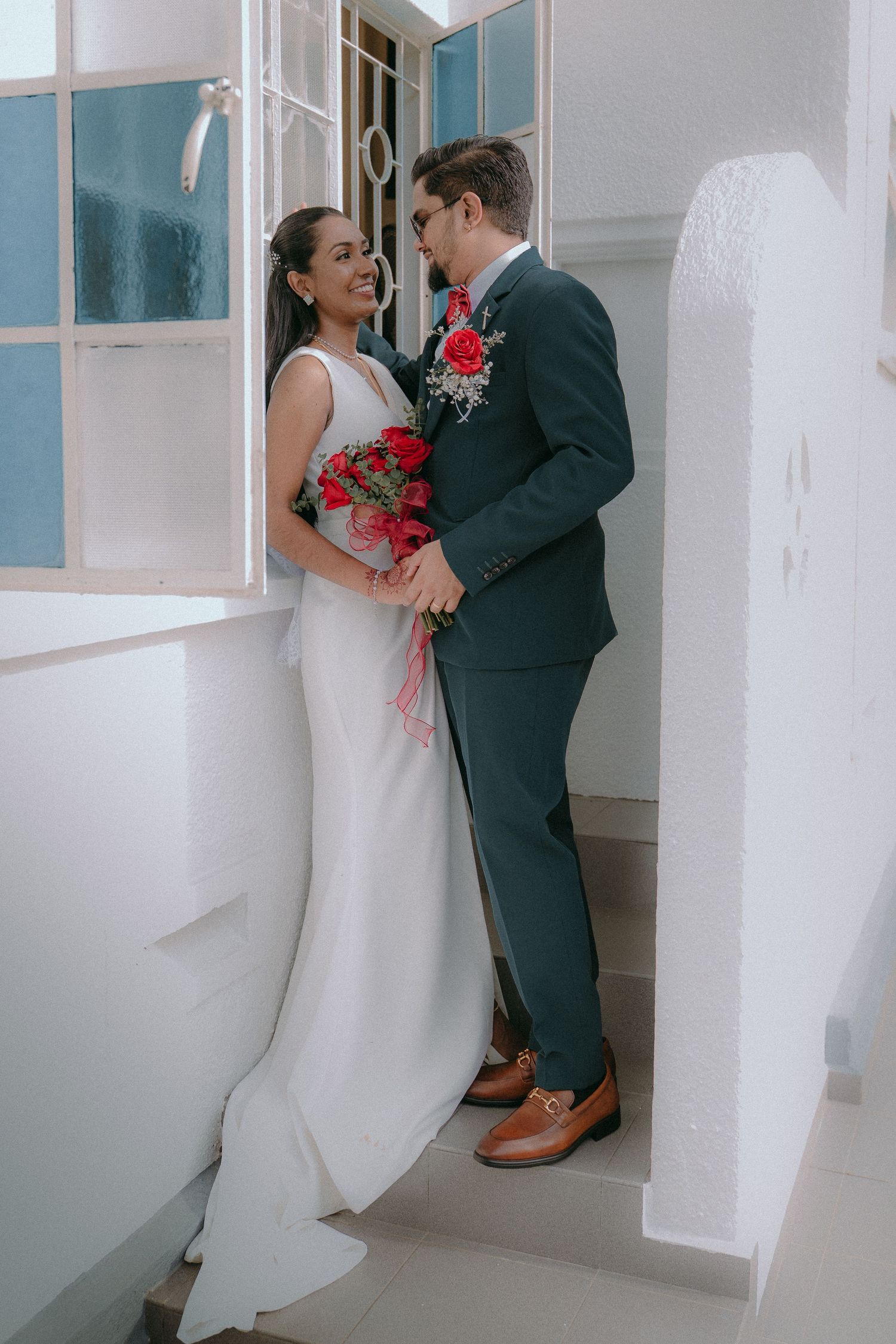 A series of tender moments captured in a bright hallway between a couple in wedding attire.