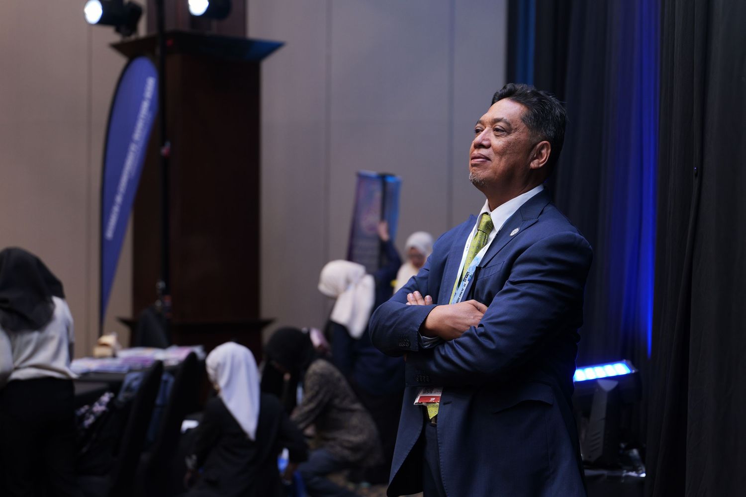 Business professionals engaging in discussion at a dimly lit conference venue with blue lighting accents.