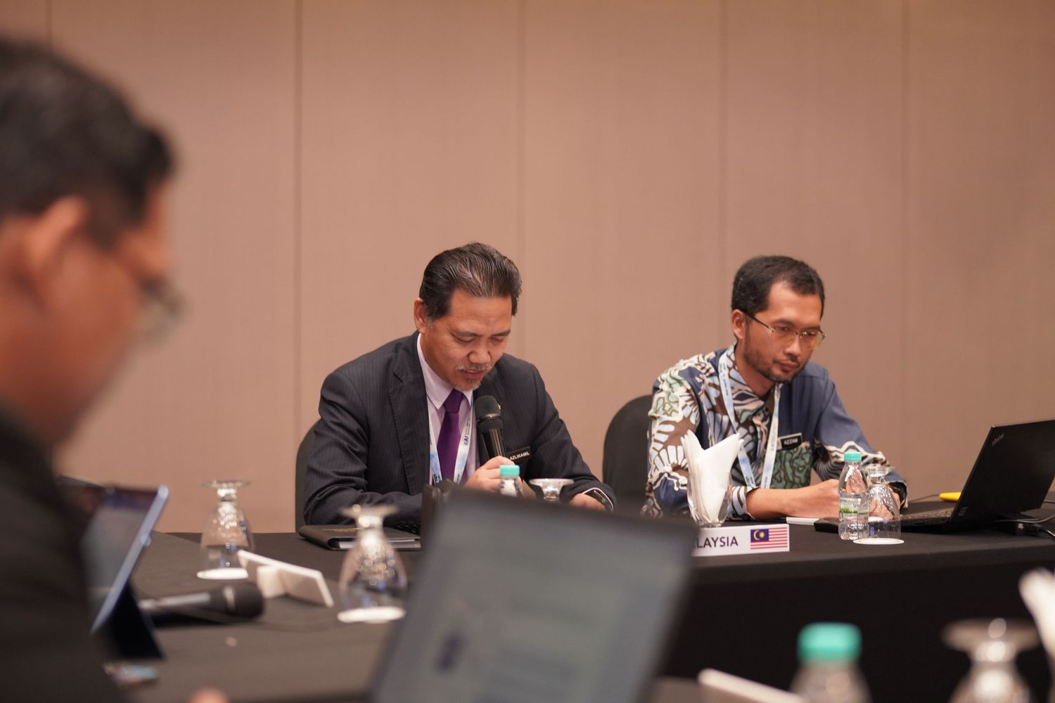 Business professionals working on laptops during a meeting in a conference room.