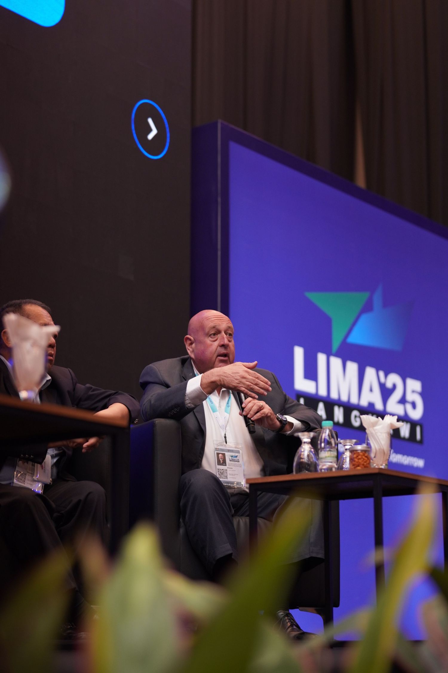 Business conference speakers seated at a panel discussion with LIMA25 logo displayed on blue backdrop.