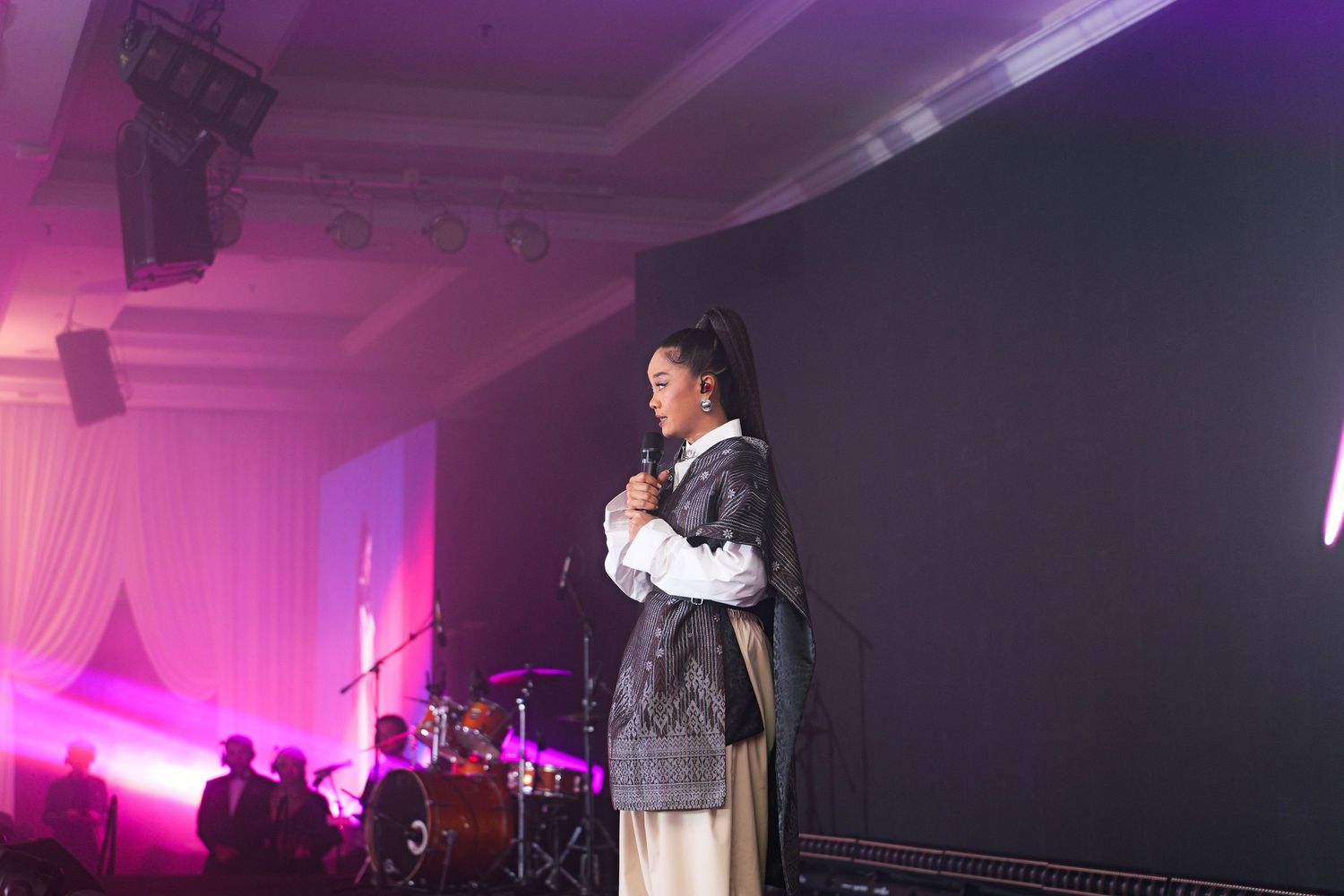 Female singer performing on stage with band at elegant corporate gala dinner.