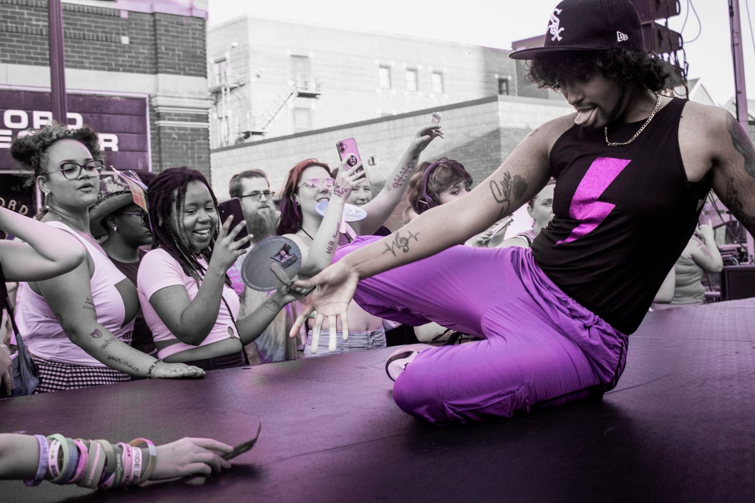Performer in black tank top and purple pants entertaining crowd during outdoor show.