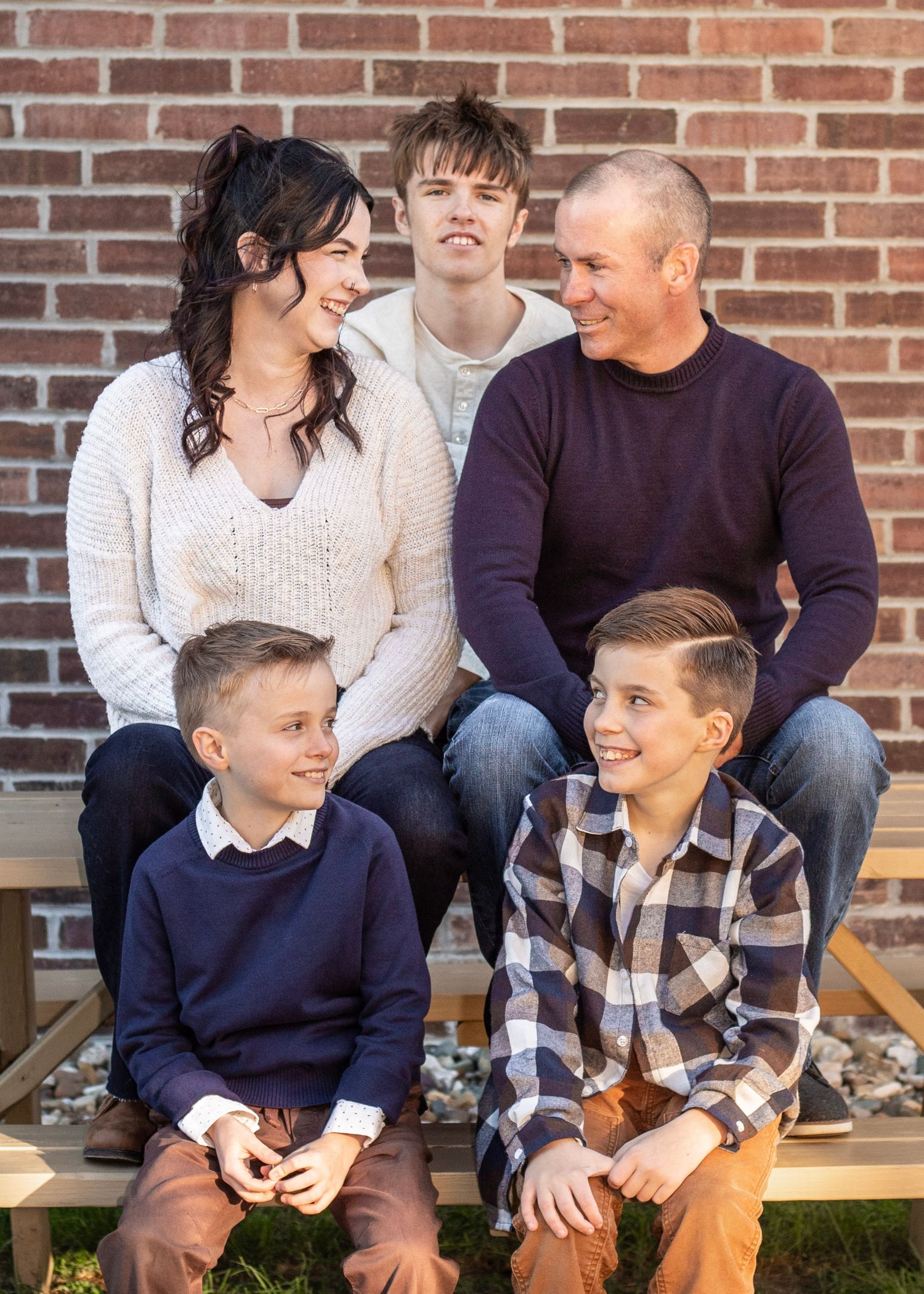 Family portrait session with coordinated navy and white outfits against a brick wall backdrop.