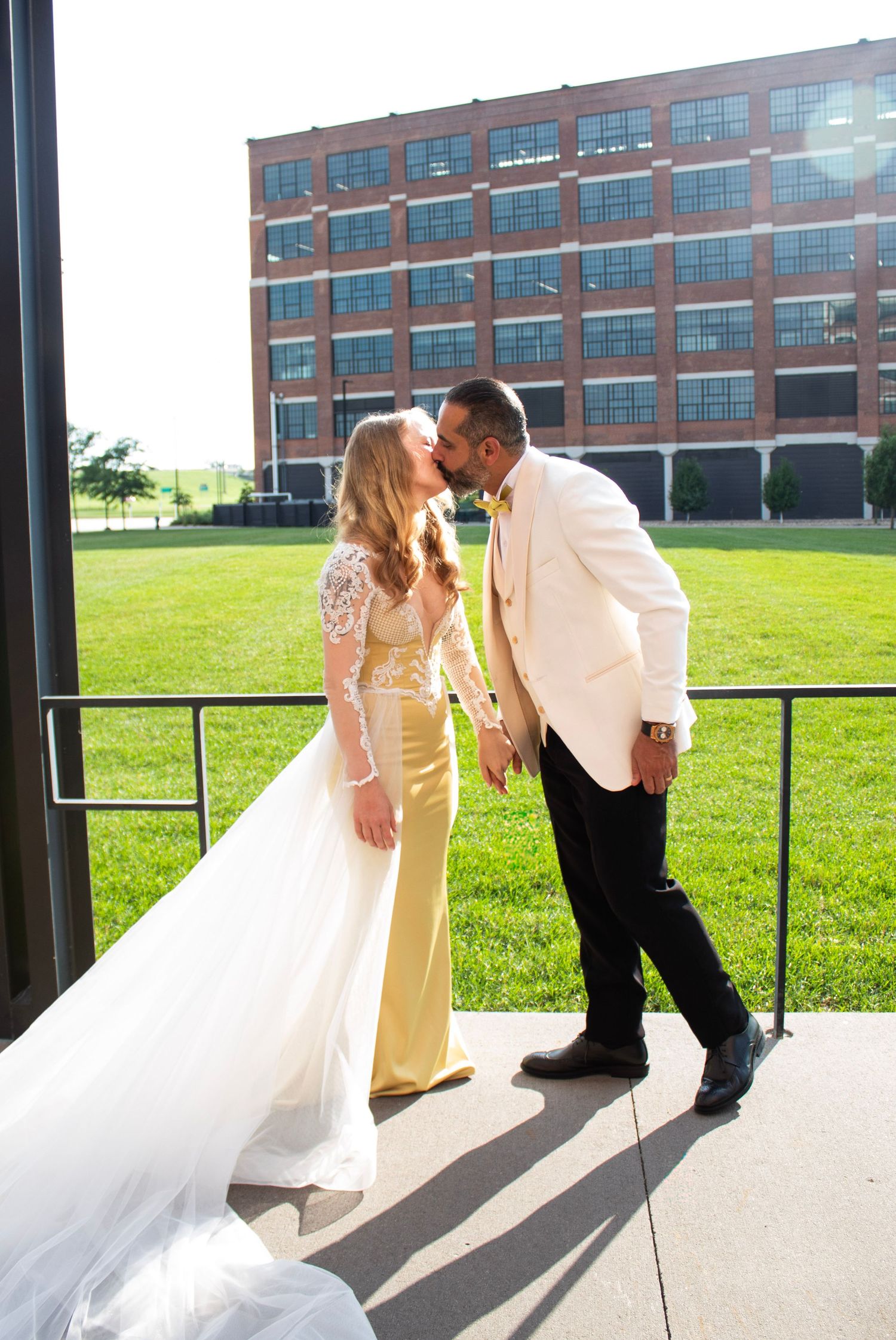 A romantic couple shares a kiss in front of a brick building with multiple poses shown in a collage-style image.