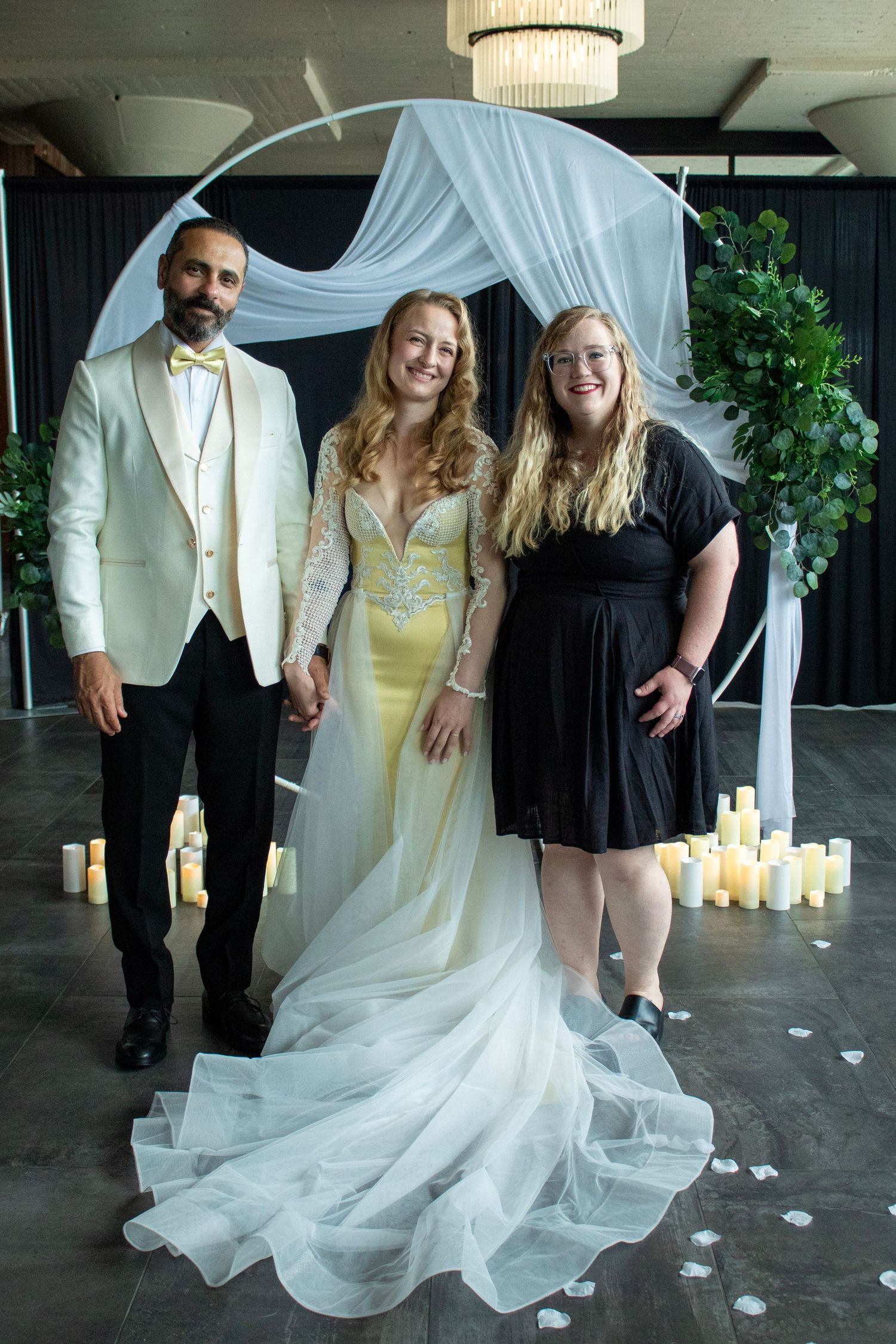 Wedding party members dance and pose together in an elegant venue decorated with white candles and greenery.