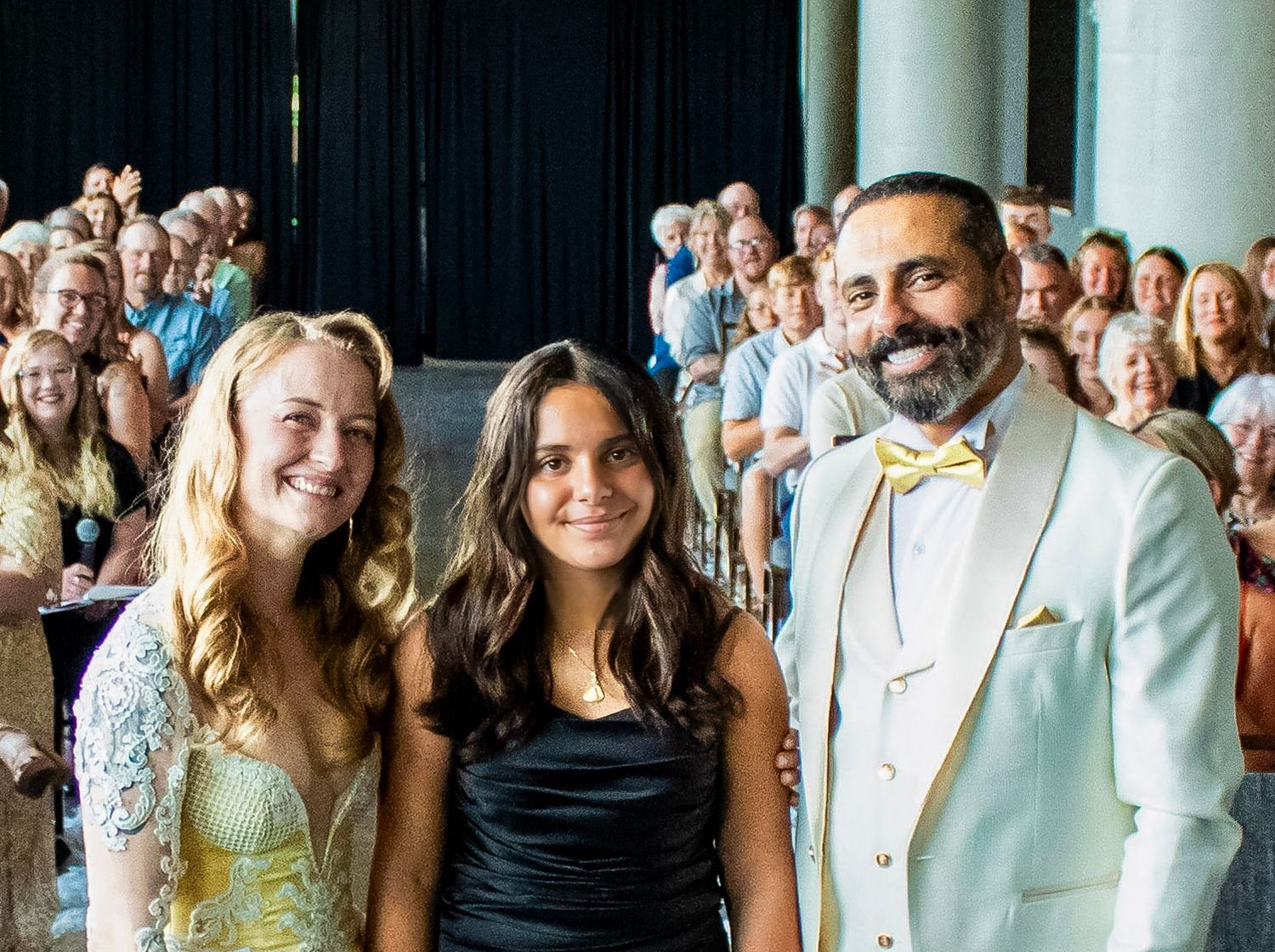 A large group of people celebrating at a wedding reception with guests smiling and posing together for a photo.