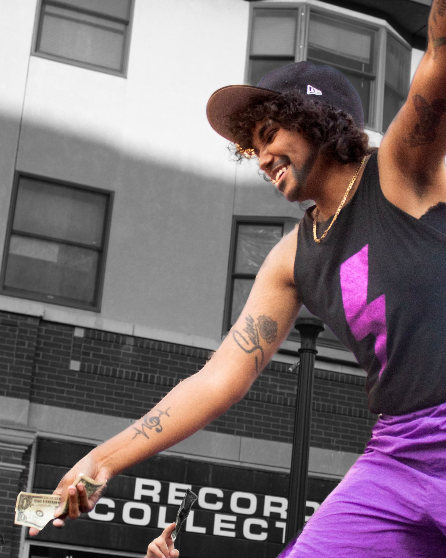 Performer in black tank top and purple outfit smiling during outdoor show.