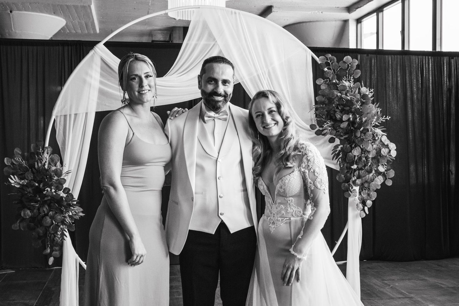 A group poses together with white umbrellas at an elegant indoor wedding celebration.