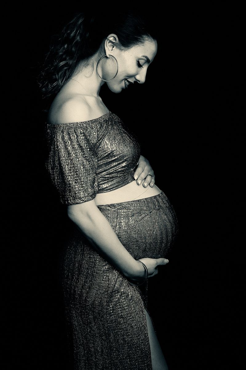 Artistic black and white portrait of expectant mother in off-shoulder dress.