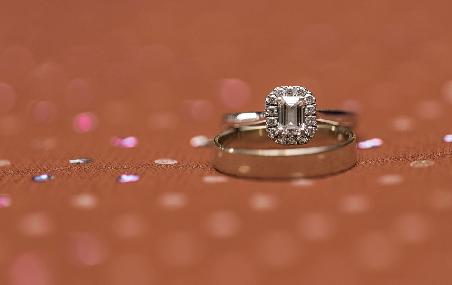Close-up of diamond engagement rings creating reflections on a rose gold surface.