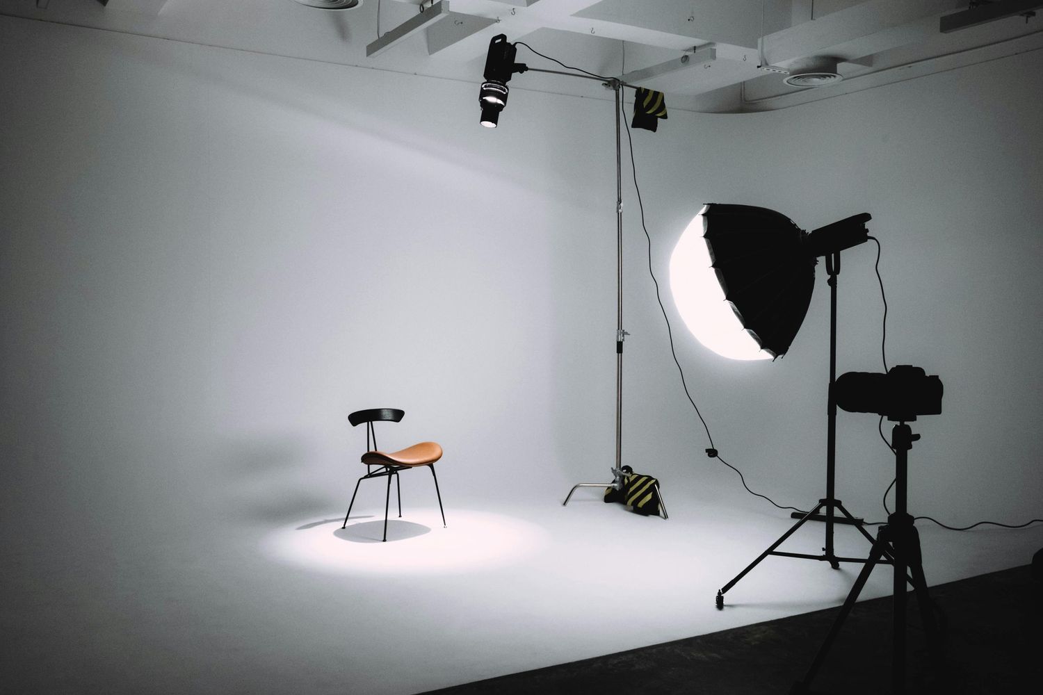 Professional photography studio setup with lighting equipment and a wooden chair against white backdrop.