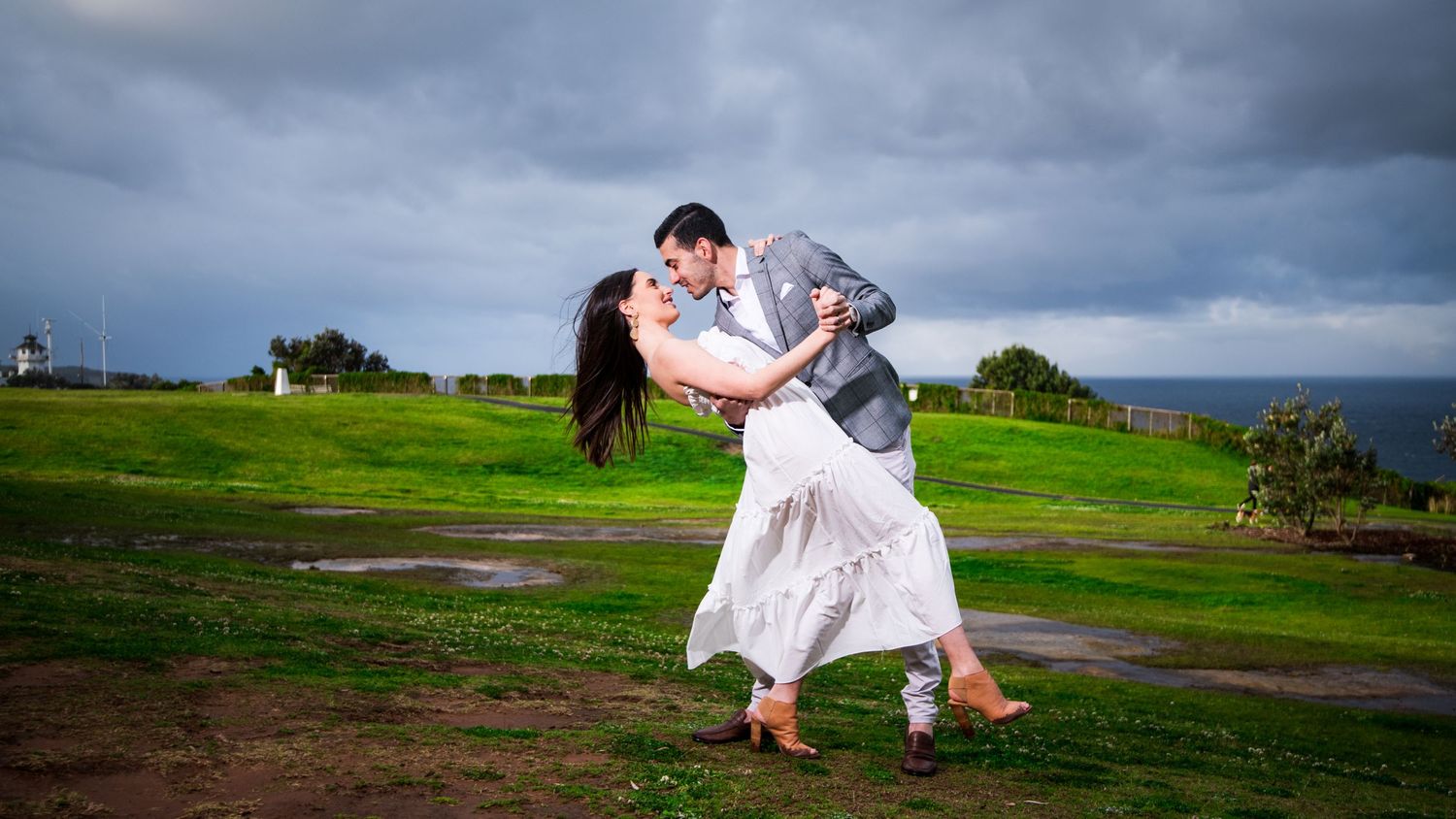 Panoramic sequence of couple walking and embracing on coastal cliffs under moody sky.