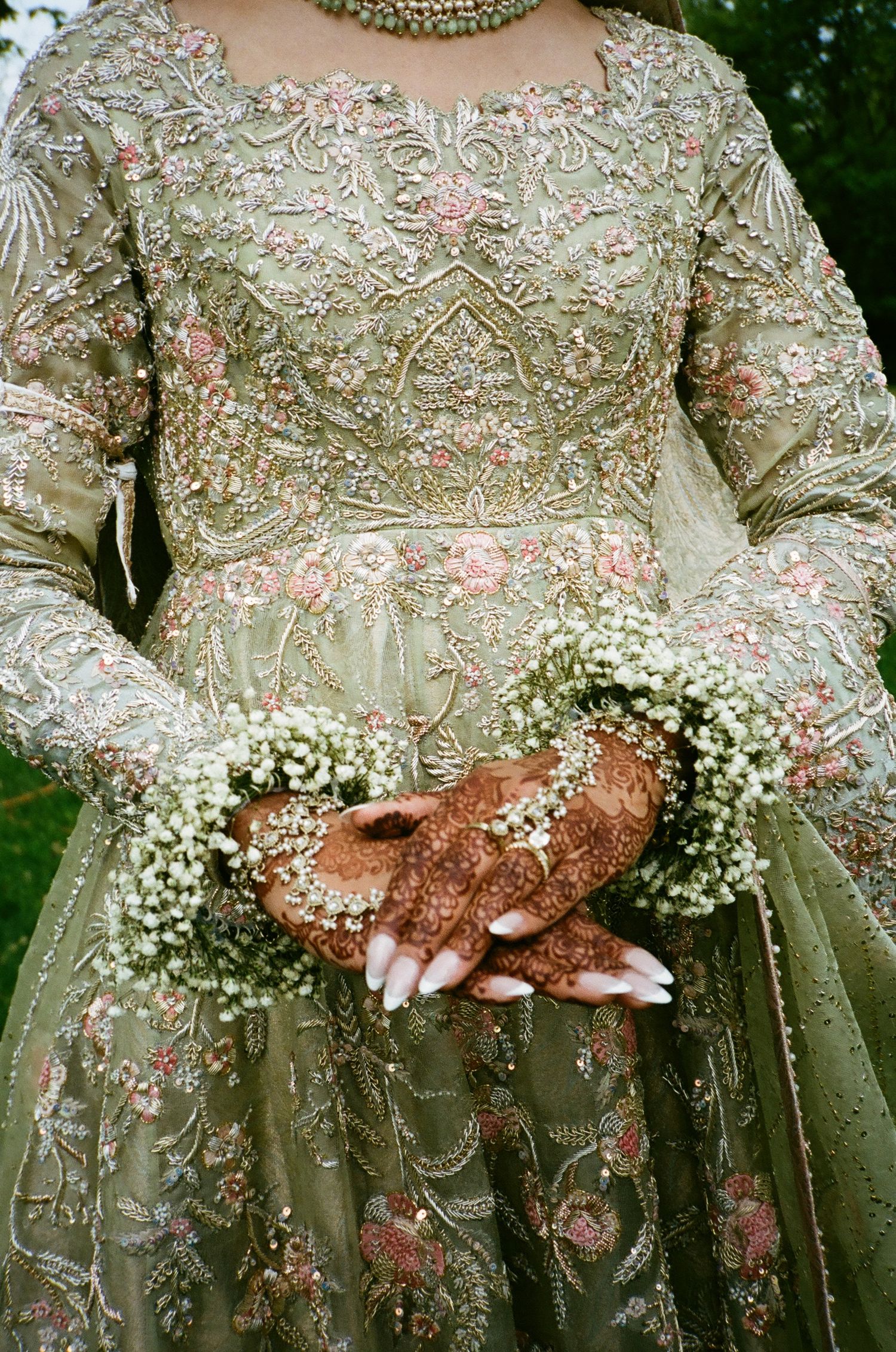 Nikkah bride glows in sage green Pakistani outfit, adorned with floral jewelry and soft glam—captured in vintage tones on 35mm film.
