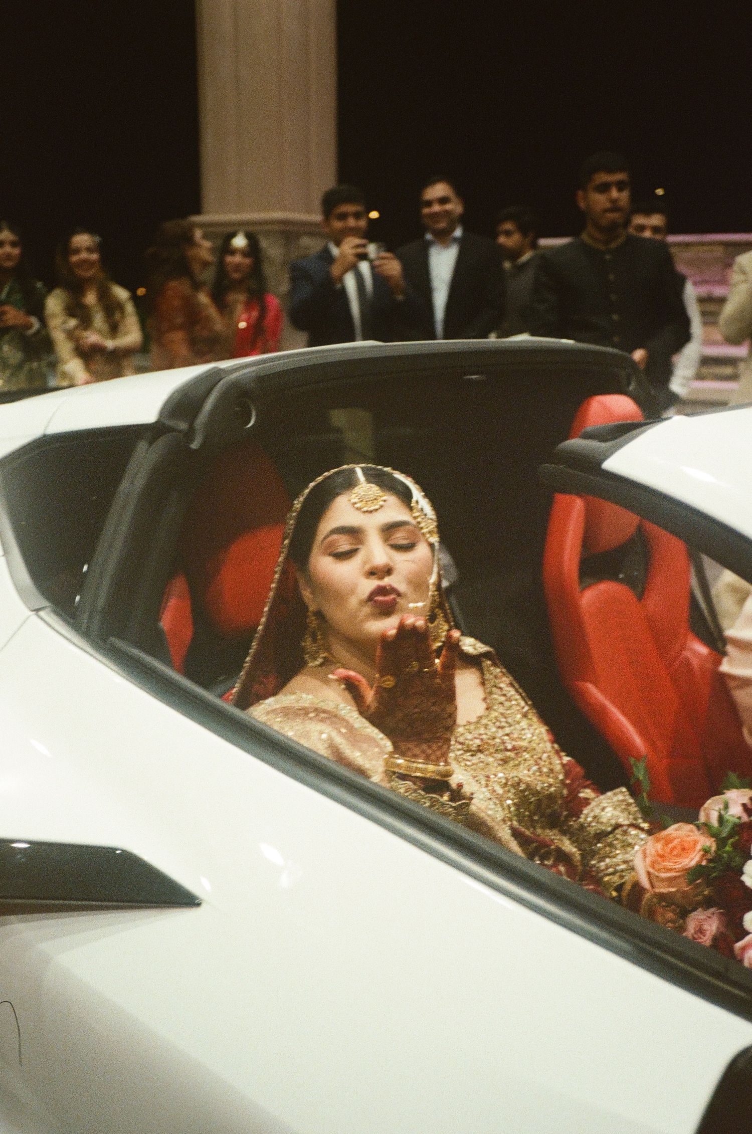 Desi bride in red lehenga blows a kiss as she departs—playful, radiant, and full of love, preserved on 35mm film forever.
south asian