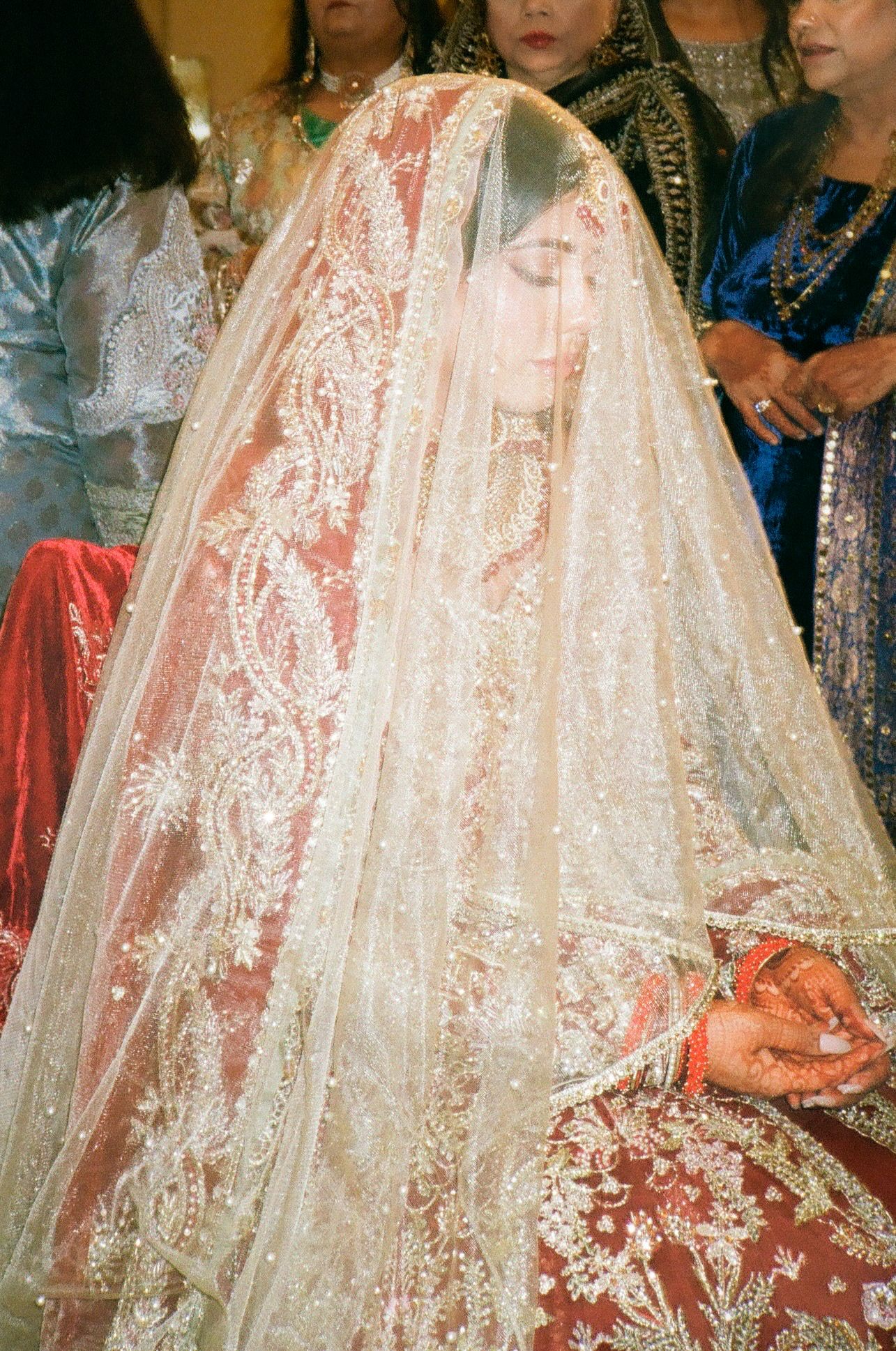 Bride glows under her red veil, seated at her Nikkah—radiant and regal, her joy immortalized on 35mm film in warm tones. south asian
