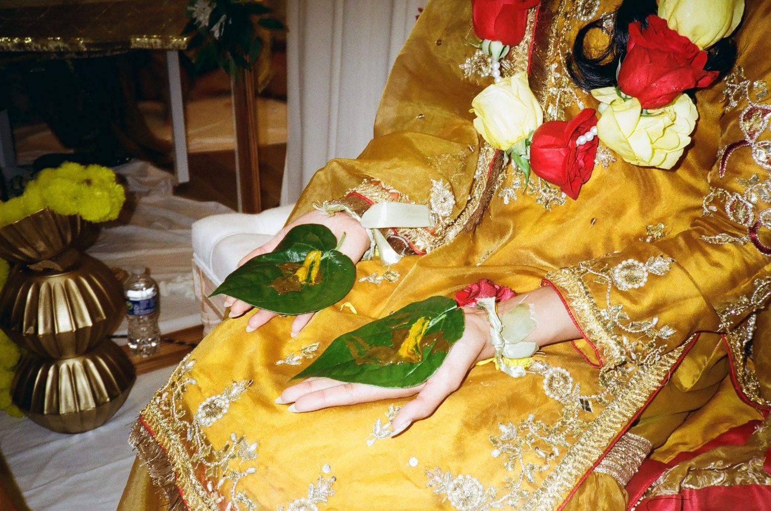 Mayoun girl in yellow holds a henna leaf, vintage tones highlighting this intimate pre-wedding ritual’s beauty and cultural significance.