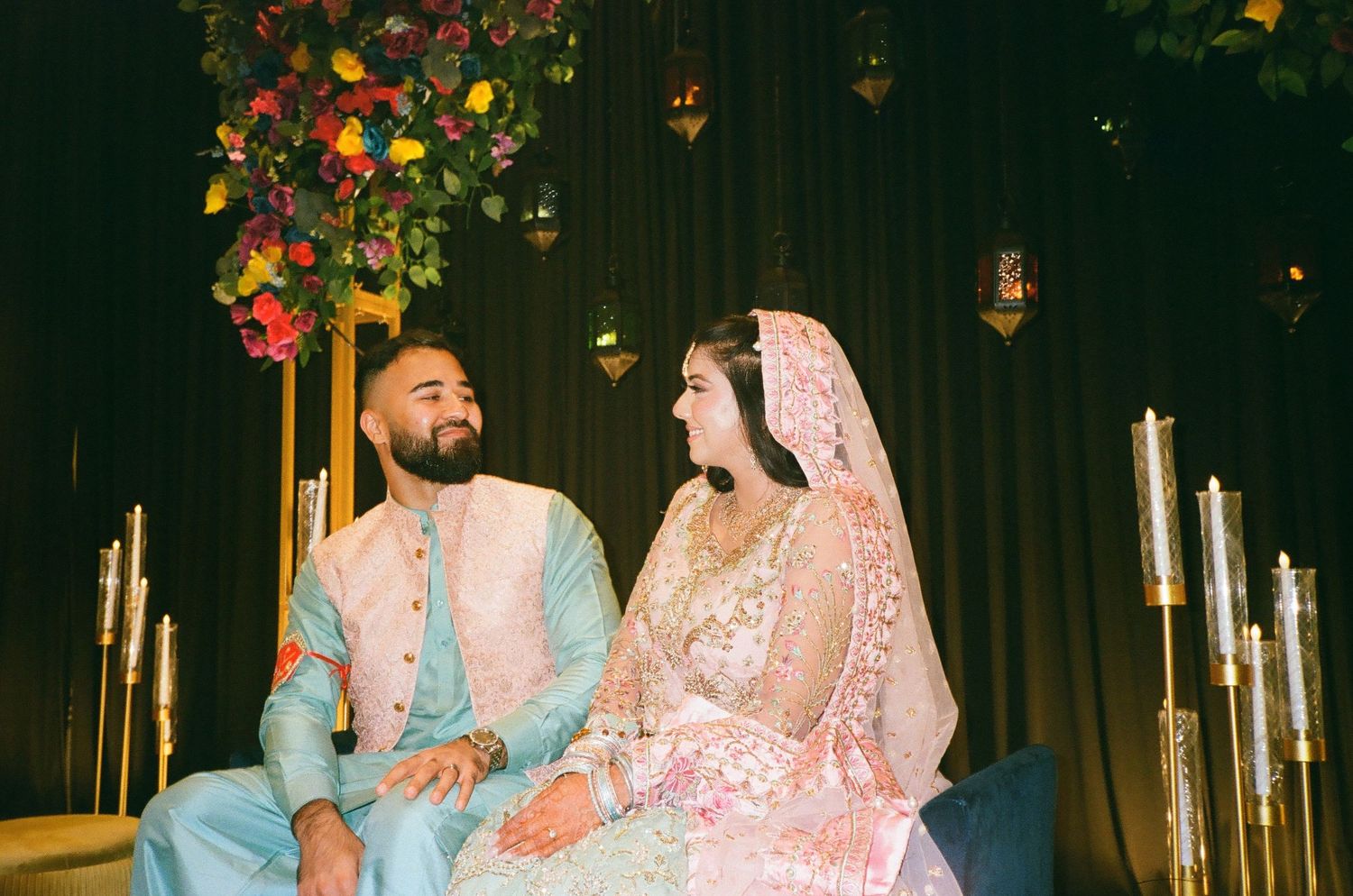 Couple shares a playful glance at their Mehndi in front of a lush floral backdrop, moments frozen beautifully on 35mm film in Chicago.