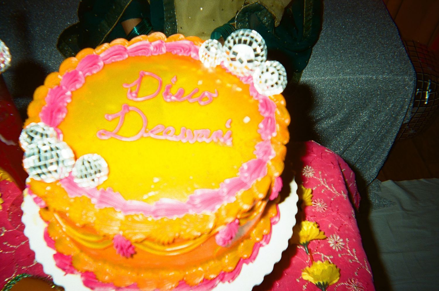 A vibrant dholki cake at a pre-wedding party in the Chicago area reads “Disco Deewani,” bursting with color and joy on nostalgic 35mm film